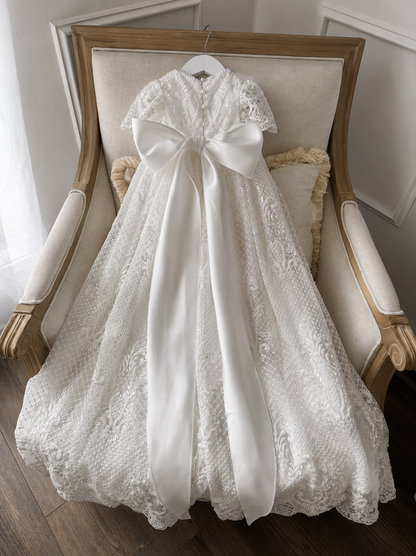 An elegant heirloom gown designed with timeless tradition in mind. Crafted from intricate lace, this gown features pearl and sequence embellishments throughout. It features delicate short sleeves, a softly structured bodice. The back is finished with delicate pearl buttons and a long mikado side belt that can be tied into a bow. The intricate lacework flows throughout the gown, creating beautiful texture and detail from every angle. 