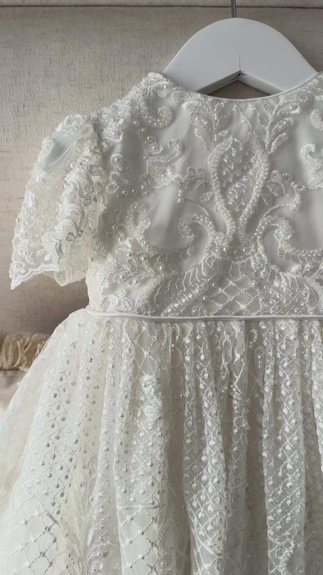 An elegant heirloom gown designed with timeless tradition in mind. Crafted from intricate lace, this gown features pearl and sequence embellishments throughout. It features delicate short sleeves, a softly structured bodice. The back is finished with delicate pearl buttons and a long mikado side belt that can be tied into a bow. The intricate lacework flows throughout the gown, creating beautiful texture and detail from every angle. 