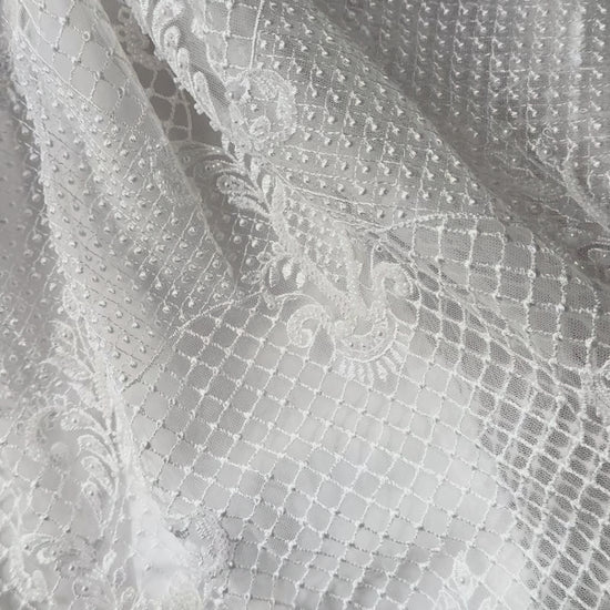 An elegant heirloom gown designed with timeless tradition in mind. Crafted from intricate lace, this gown features pearl and sequence embellishments throughout. It features delicate short sleeves, a softly structured bodice. The back is finished with delicate pearl buttons and a long mikado side belt that can be tied into a bow. The intricate lacework flows throughout the gown, creating beautiful texture and detail from every angle. 
