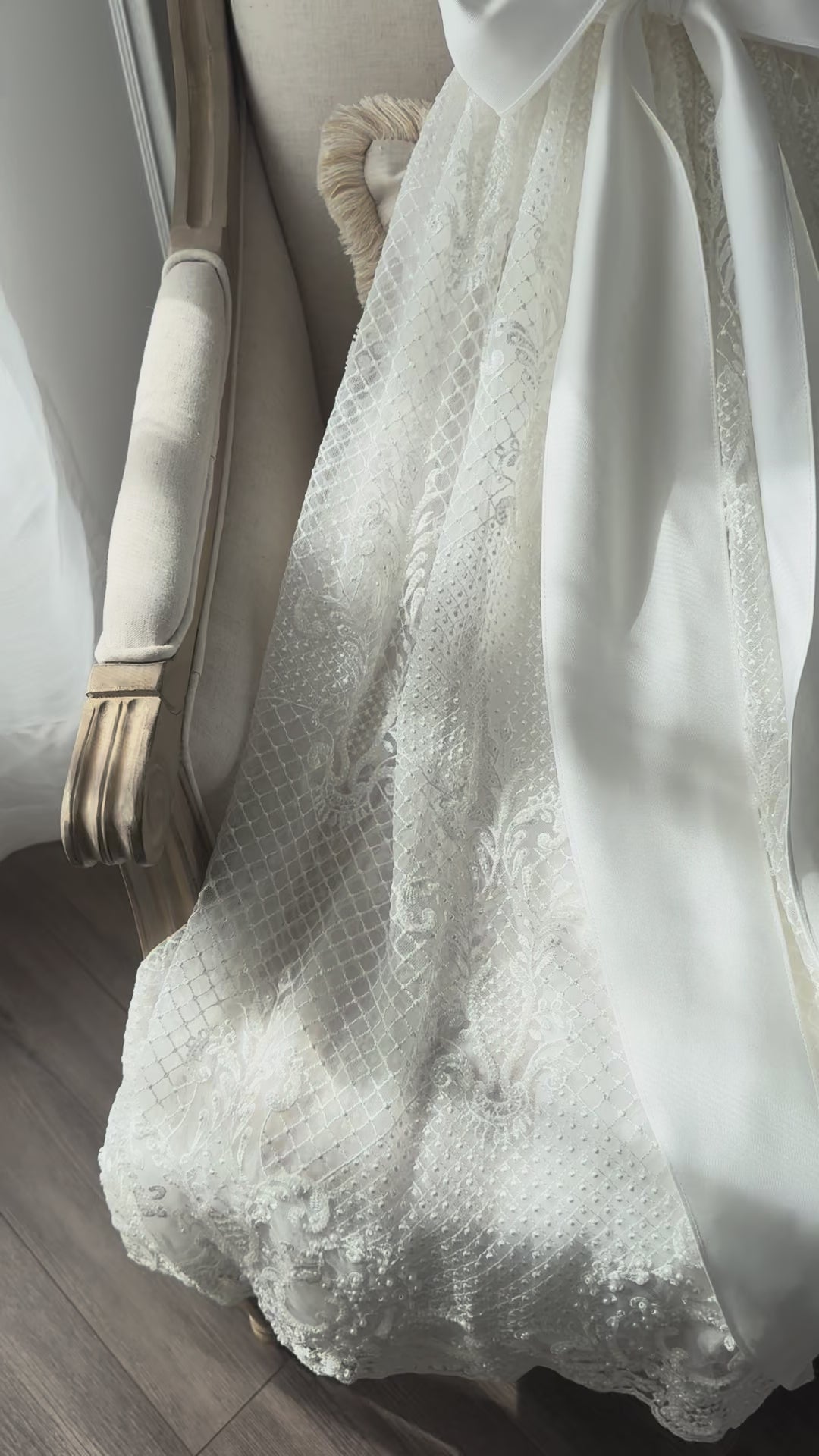 An elegant heirloom gown designed with timeless tradition in mind. Crafted from intricate lace, this gown features pearl and sequence embellishments throughout. It features delicate short sleeves, a softly structured bodice. The back is finished with delicate pearl buttons and a long mikado side belt that can be tied into a bow. The intricate lacework flows throughout the gown, creating beautiful texture and detail from every angle. 