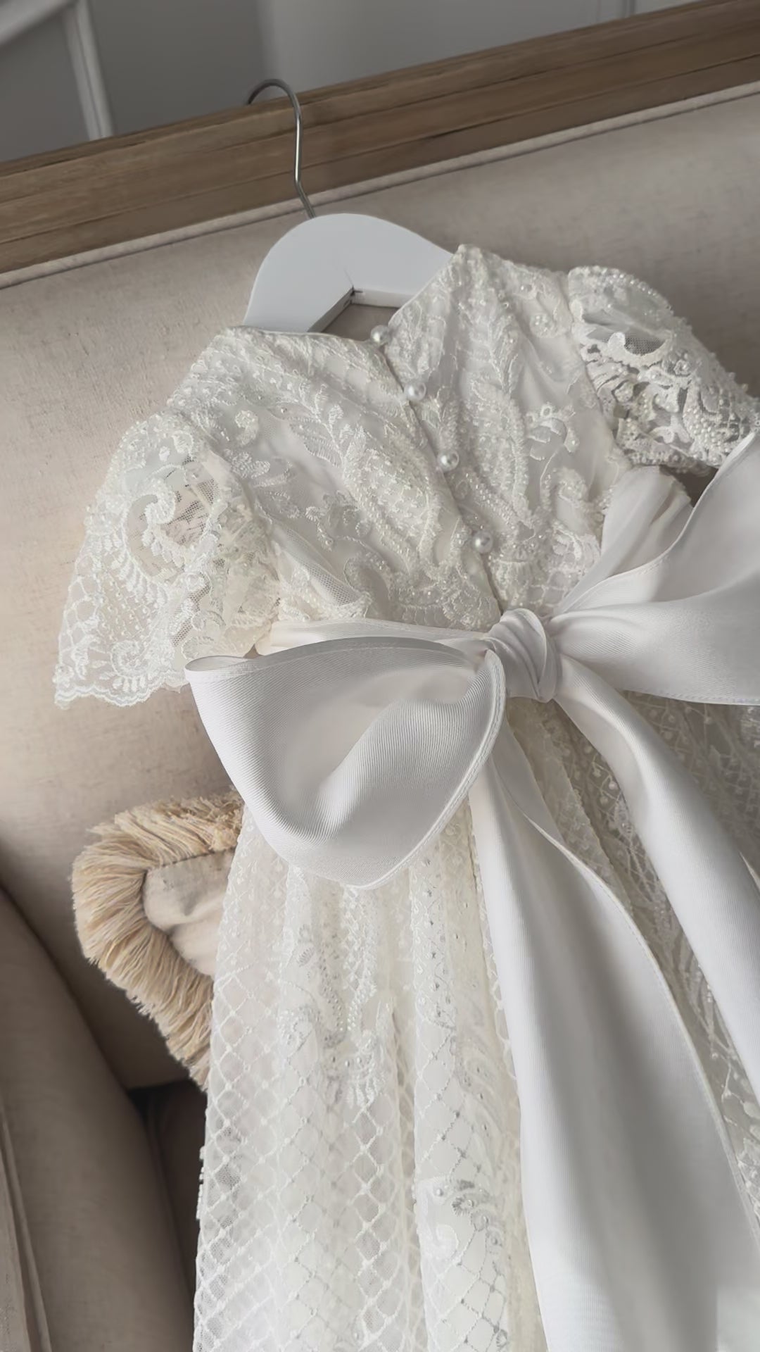 An elegant heirloom gown designed with timeless tradition in mind. Crafted from intricate lace, this gown features pearl and sequence embellishments throughout. It features delicate short sleeves, a softly structured bodice. The back is finished with delicate pearl buttons and a long mikado side belt that can be tied into a bow. The intricate lacework flows throughout the gown, creating beautiful texture and detail from every angle. 